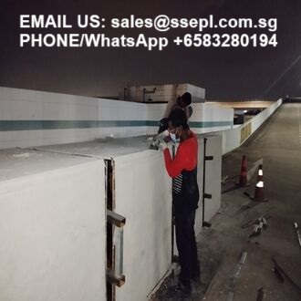 Nighttime rooftop scene with two workers on a concrete barrier; overlaid text shows an email and WhatsApp phone number for contact.