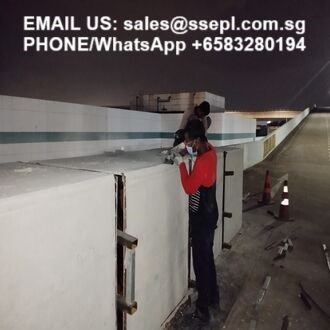Two workers on a concrete wall at night, one in a red shirt, with contact email and WhatsApp/phone text shown at the top of the image.