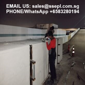 Two workers atop a white concrete barrier at night; contact info for sales (email and WhatsApp number) is overlaid at the top.