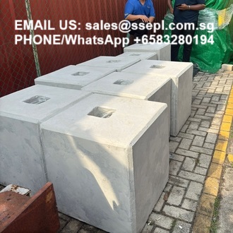 Row of large gray hollow-core concrete blocks on a paved outdoor area, with white text overlay showing an email address and WhatsApp number for inquiries.