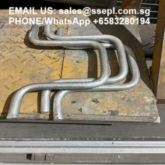 Bent metal tubes stacked on a worn workshop bench with contact information text overlaid at the top.